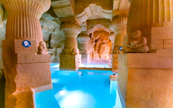 Thermal spa area with stone columns and blue water at Caldea, Andorra.