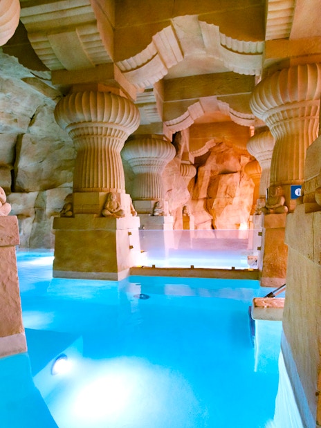 Thermal spa area with stone columns and blue water at Caldea, Andorra.