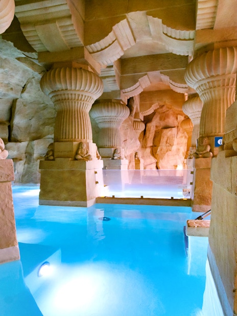 Thermal spa area with stone columns and blue water at Caldea, Andorra.