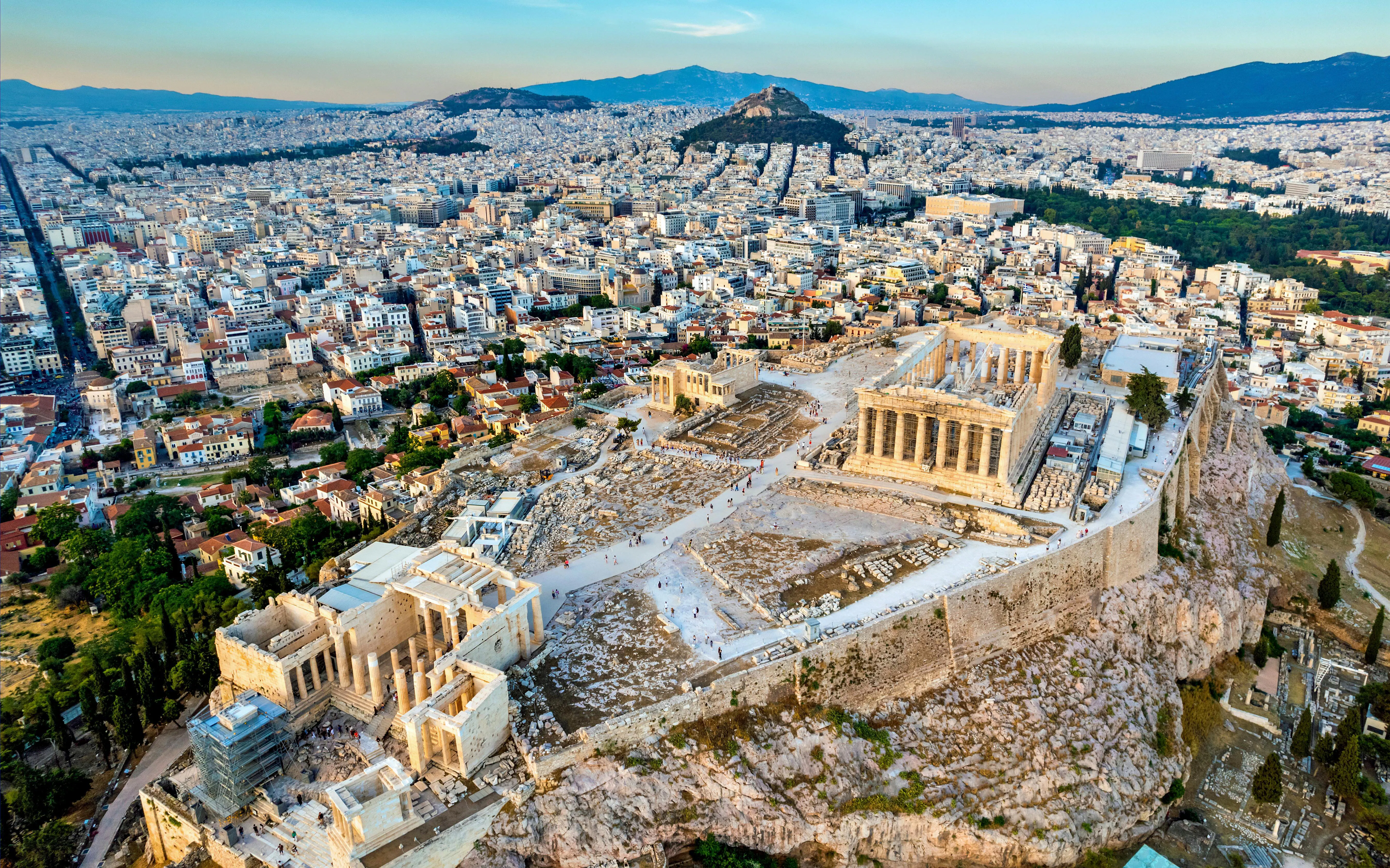 Aerial view of the Acropolis of Athens, featuring the Parthenon, Erechtheion, and Propylaea with cityscape.