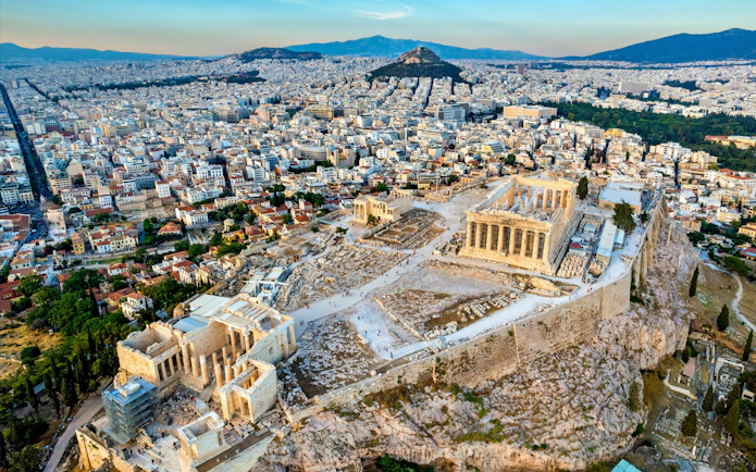Aerial view of the Acropolis of Athens, featuring the Parthenon, Erechtheion, and Propylaea with cityscape.