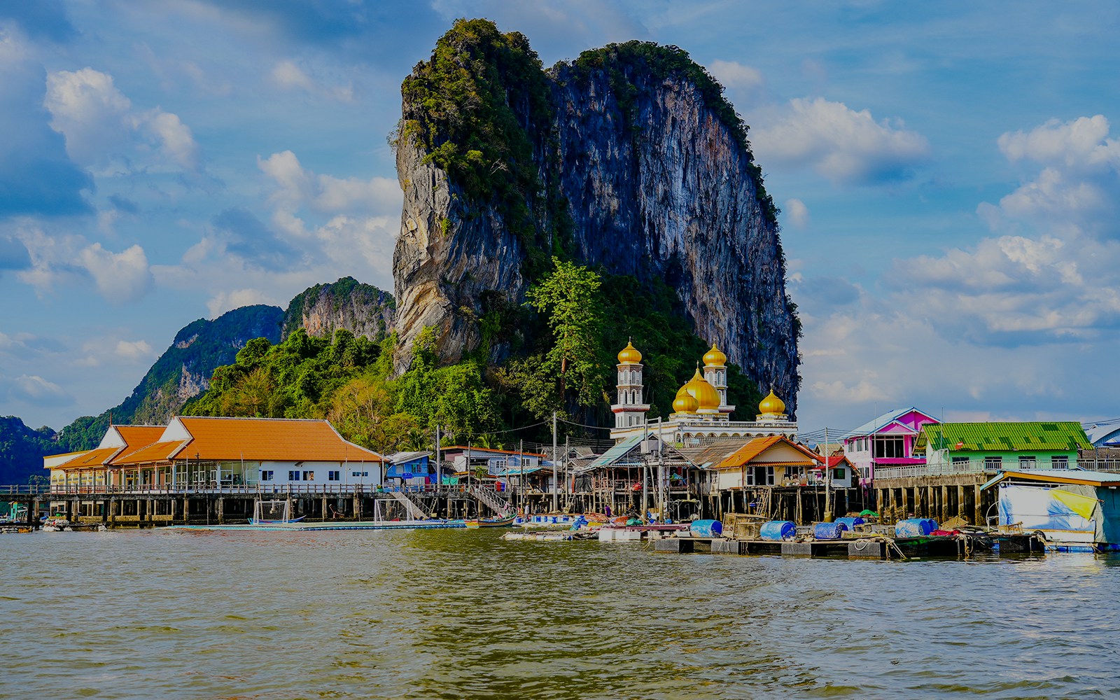 Floating fishing village of Koh Panyee with limestone cliff and colorful buildings.
