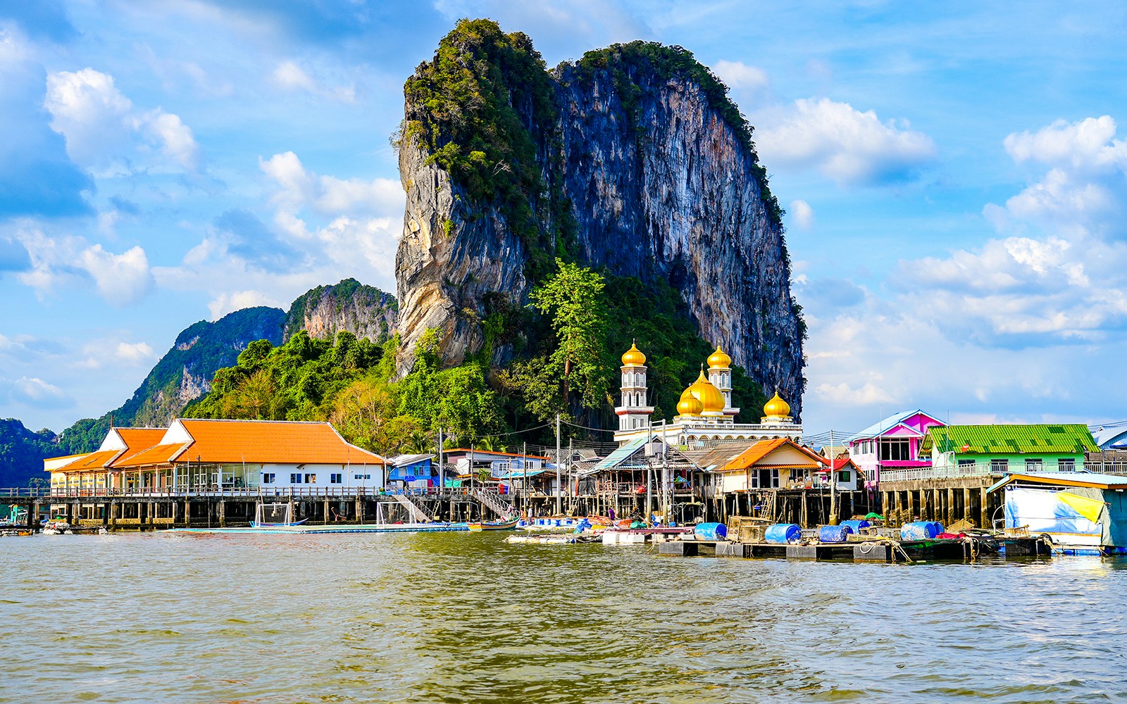 Floating fishing village of Koh Panyee with limestone cliff and colorful buildings.