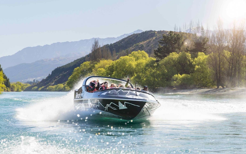 Jet boat speeding on Kawarau River with passengers enjoying the ride.