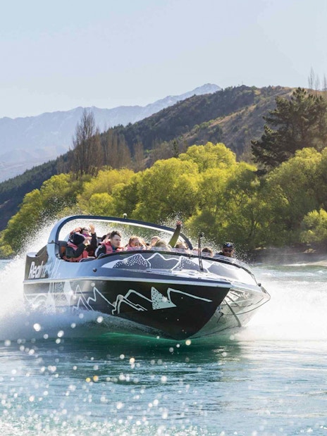 Jet boat speeding on Kawarau River with passengers enjoying the ride.