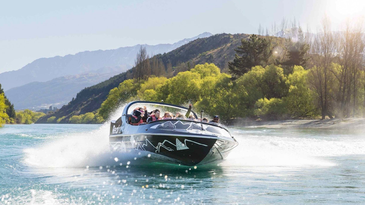 Jet boat speeding on Kawarau River with passengers enjoying the ride.