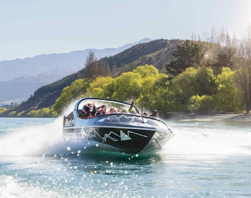 Jet boat speeding on Kawarau River with passengers enjoying the ride.