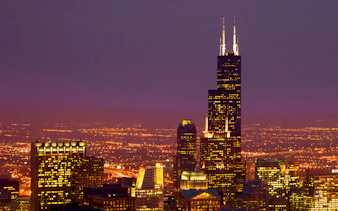 Willis Tower illuminated at night with Chicago skyline.
