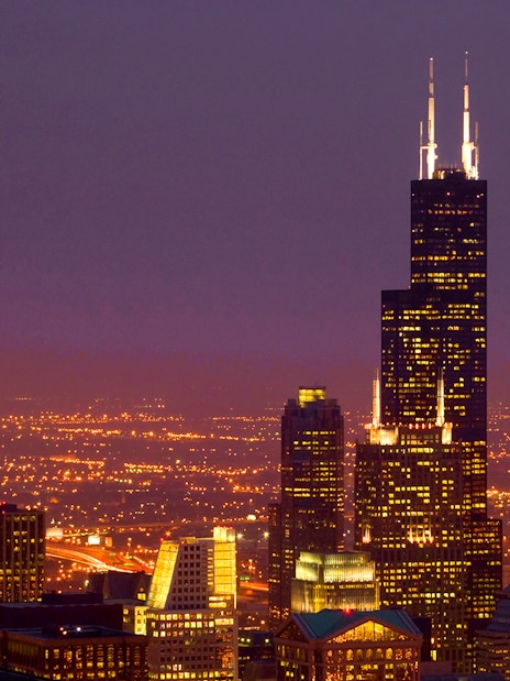 Willis Tower illuminated at night with Chicago skyline.