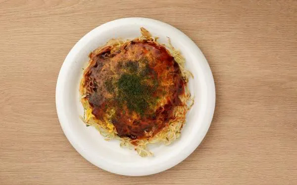 Hiroshima-style okonomiyaki on a plate, part of a tasting tour at Micchan Sohonten Orizuru Tower, Hiroshima.