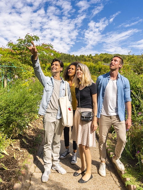 Visitors exploring Giverny Garden with a guide pointing out features.