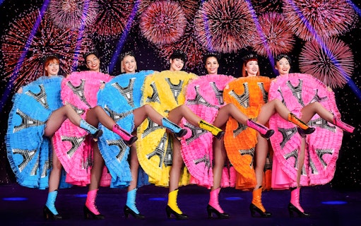 Cabaret dancers performing at New Year's Eve dinner party in Paris with fireworks.
