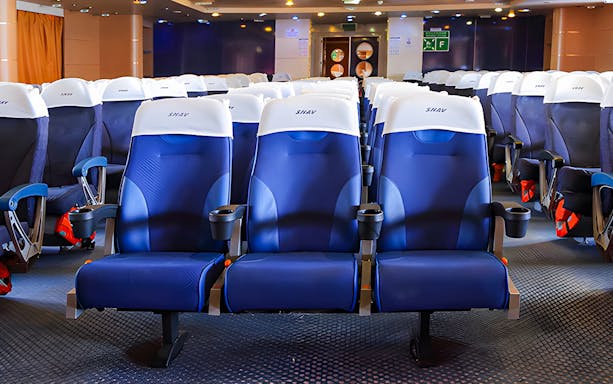Comfortable seating on SNAV Ferry with blue and white chairs in a spacious cabin.
