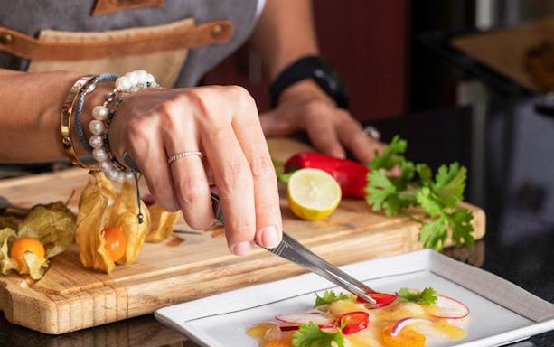Private chef plating a dish with radishes and herbs during an underground dining experience.