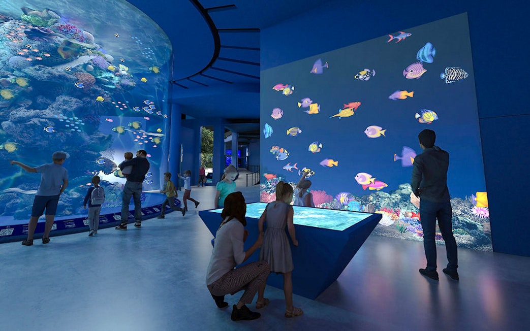 Colourful fishes in large tank at Singapore Oceanarium with visitors observing.