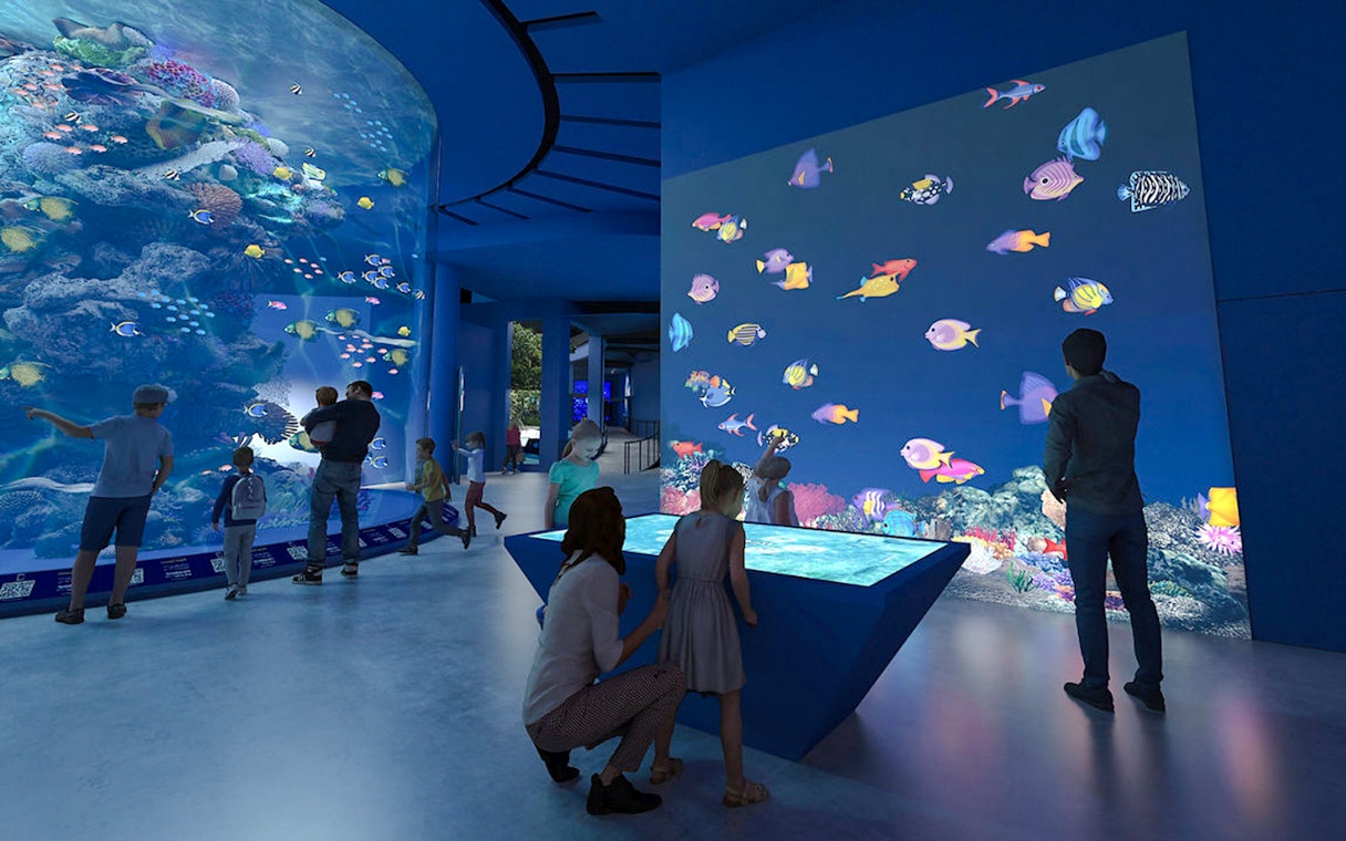 Colourful fishes in large tank at Singapore Oceanarium with visitors observing.