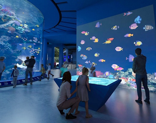 Colourful fishes in large tank at Singapore Oceanarium with visitors observing.
