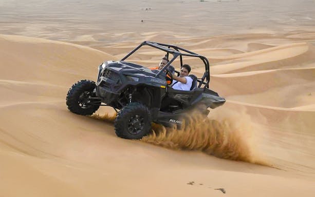 Dune buggy driving through sand dunes in Dubai desert.