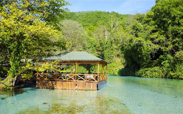 Gazebo by Blue Eye water spring surrounded by lush greenery in Albania.