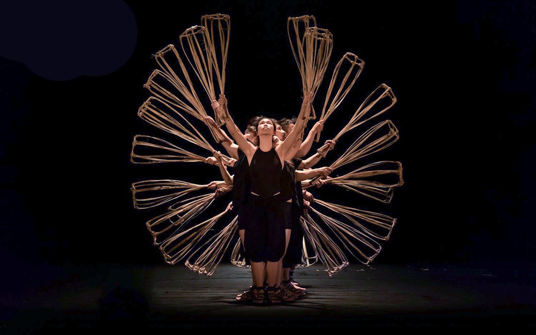 Performers at A O Show circus holding bamboo props in a synchronized formation.