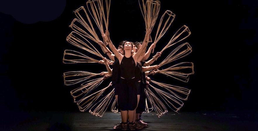Performers at A O Show circus holding bamboo props in a synchronized formation.