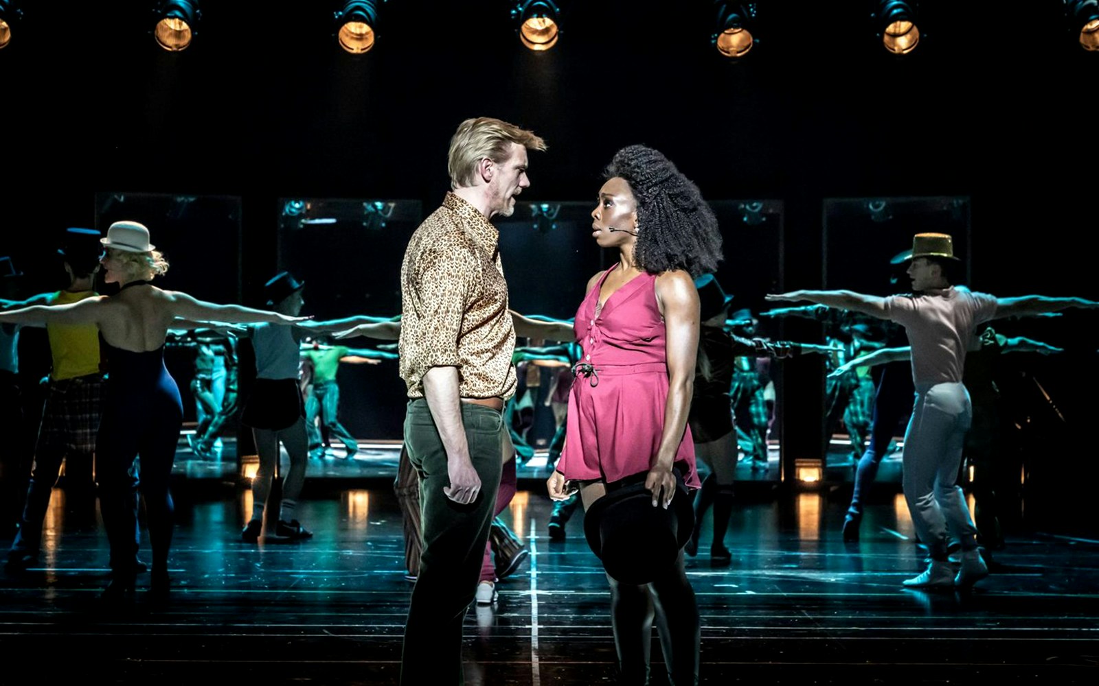 Performers on stage during "A Chorus Line" musical, with dancers in the background.