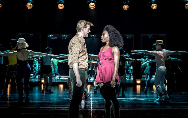 Performers on stage during "A Chorus Line" musical, with dancers in the background.