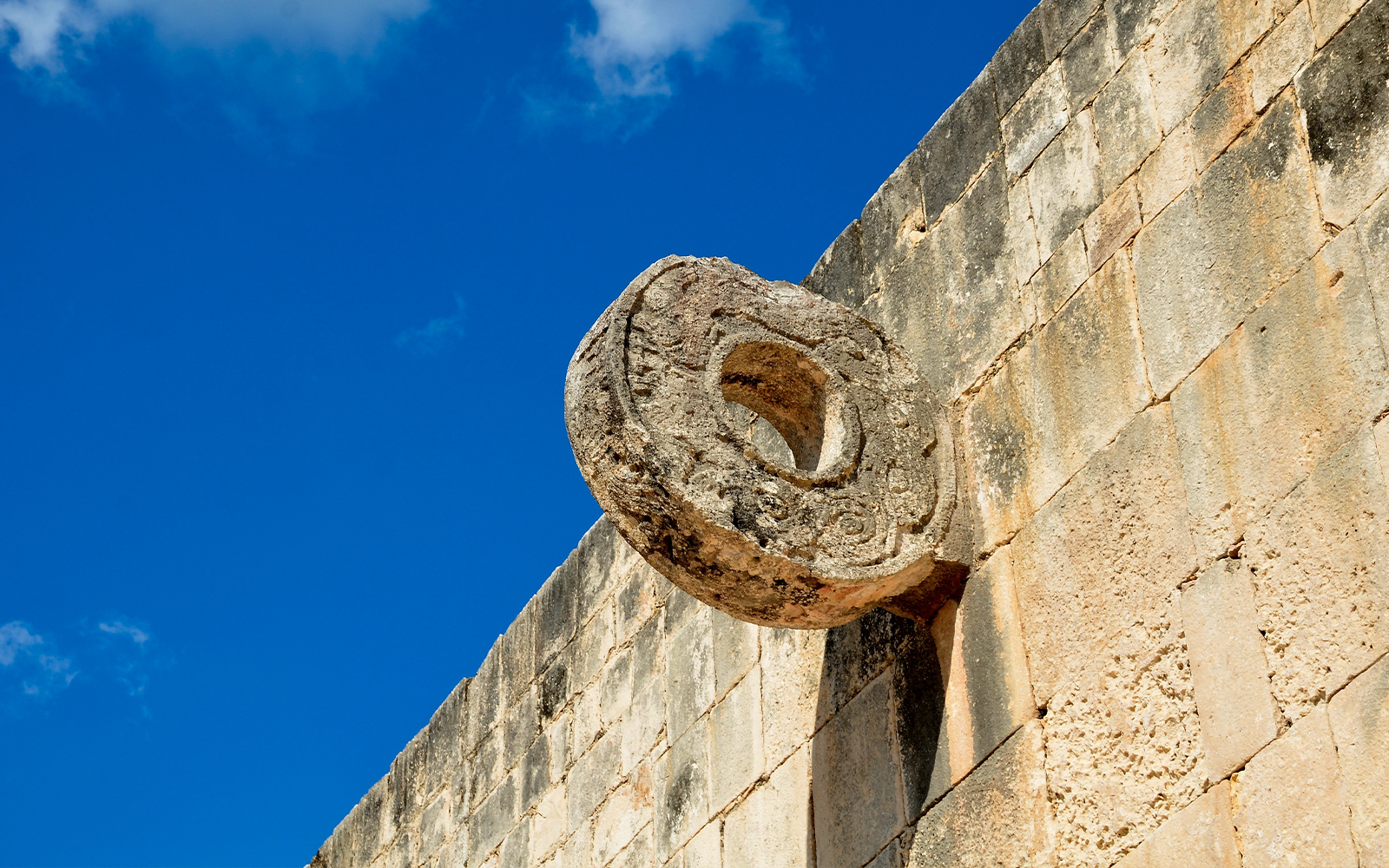 Chichen Itza Ball Court stone ring against a blue sky.