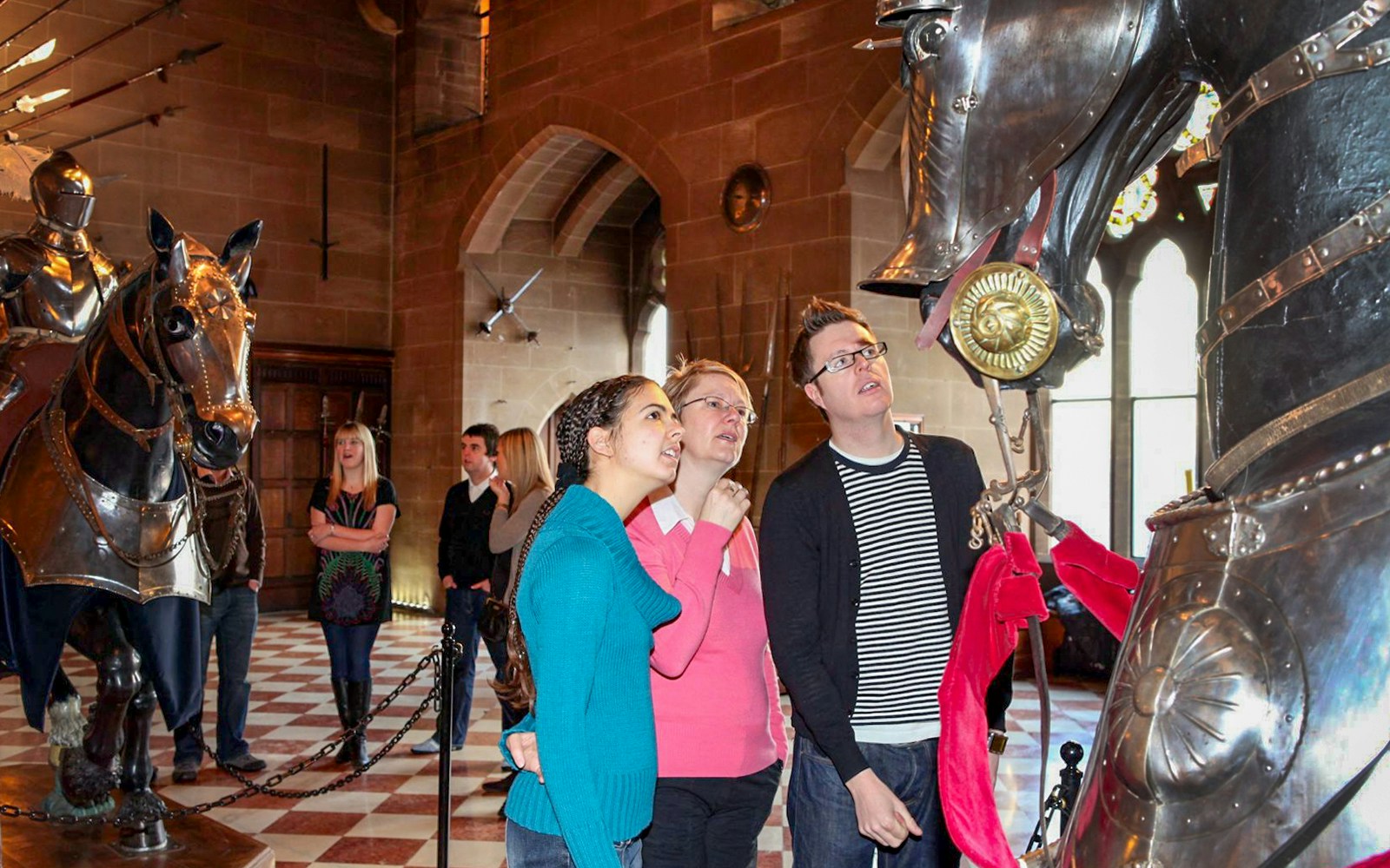 Visitors observing knight armor display at Warwick Castle.