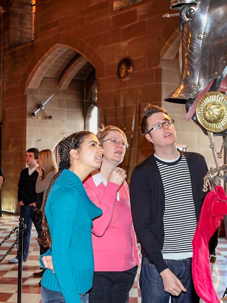 Visitors observing knight armor display at Warwick Castle.