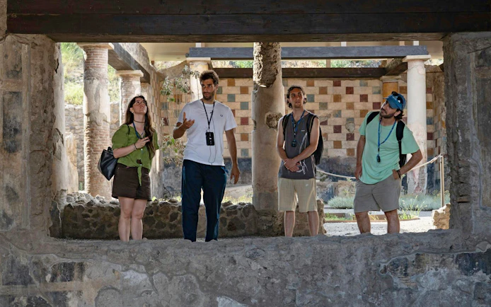 Tourists exploring ancient ruins on a guided tour in Pompeii, Italy.