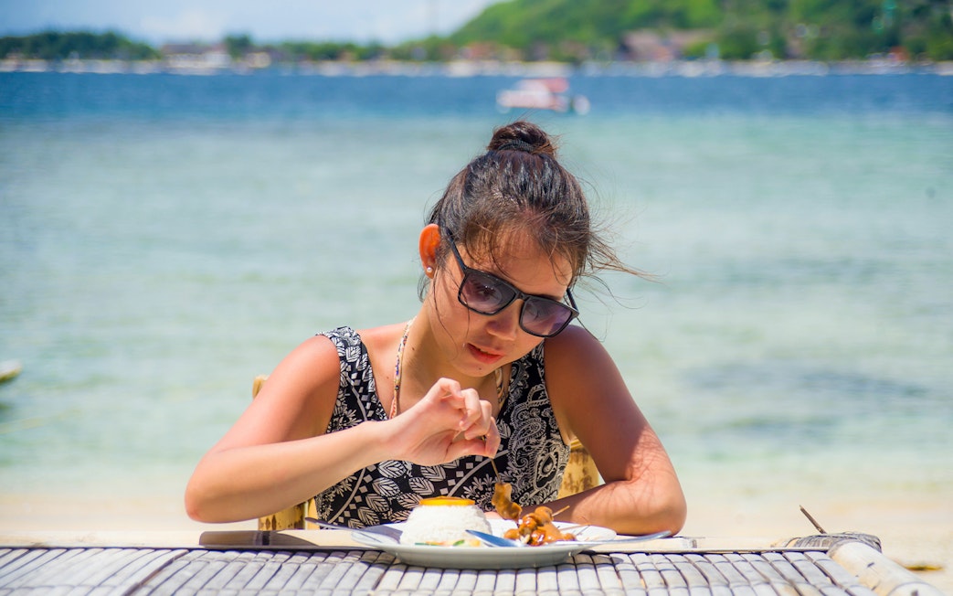 Tourist enjoying a meal by the beach on West Nusa Penida Island, Bali, Indonesia.