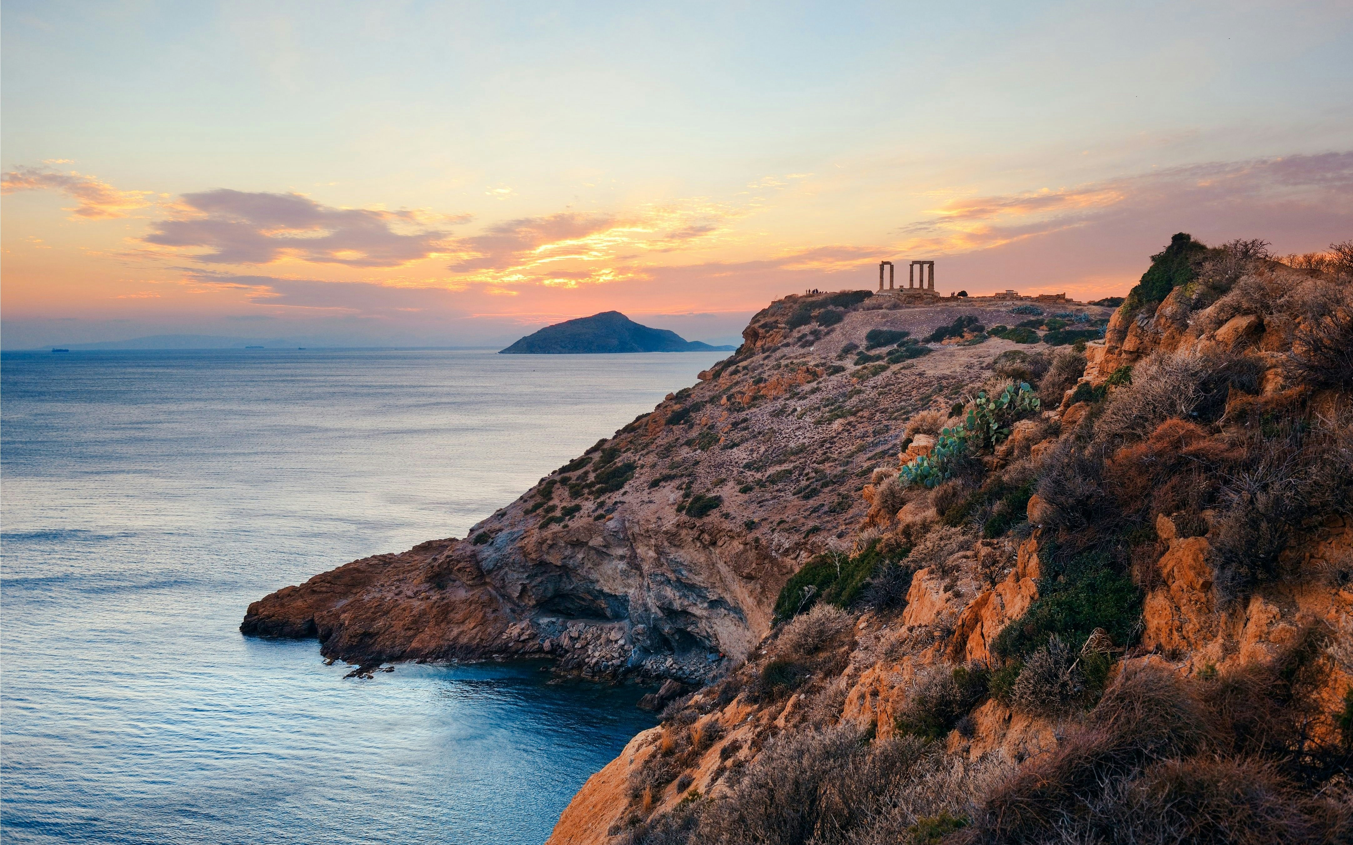 Temple of Poseidon on a cliff overlooking the Aegean Sea at sunset.