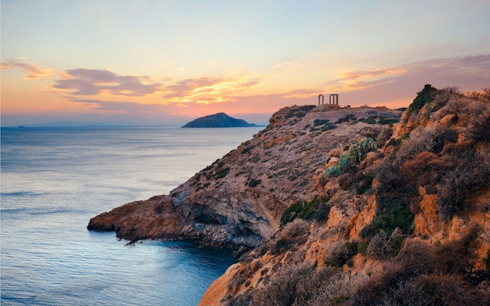 Temple of Poseidon on a cliff overlooking the Aegean Sea at sunset.