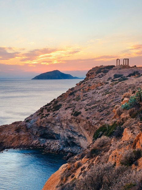 Temple of Poseidon on a cliff overlooking the Aegean Sea at sunset.