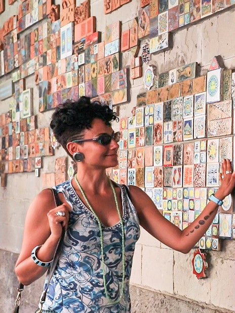 Woman admiring colorful tiles on a wall in Via dell'Arte, Italy.