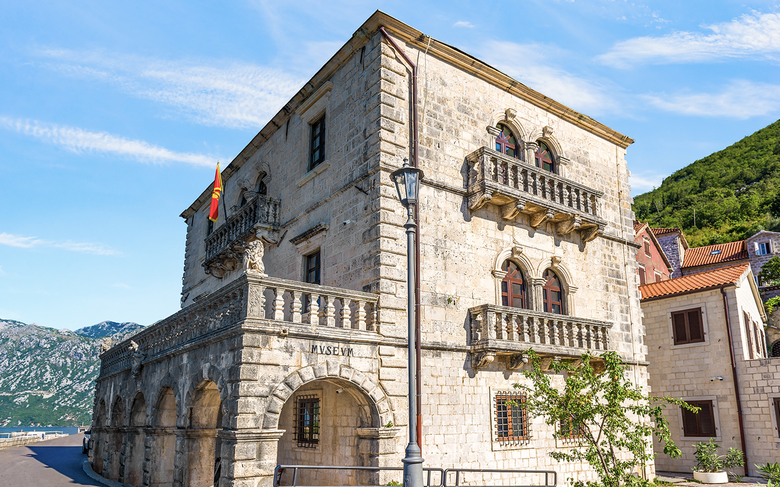 Historic stone building of the Museum of Perast city with arched windows and balconies.