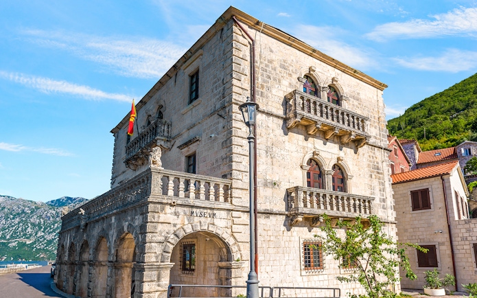 Historic stone building of the Museum of Perast city with arched windows and balconies.