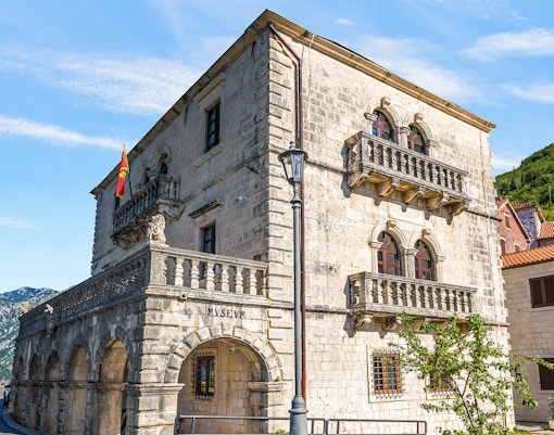 Historic stone building of the Museum of Perast city with arched windows and balconies.