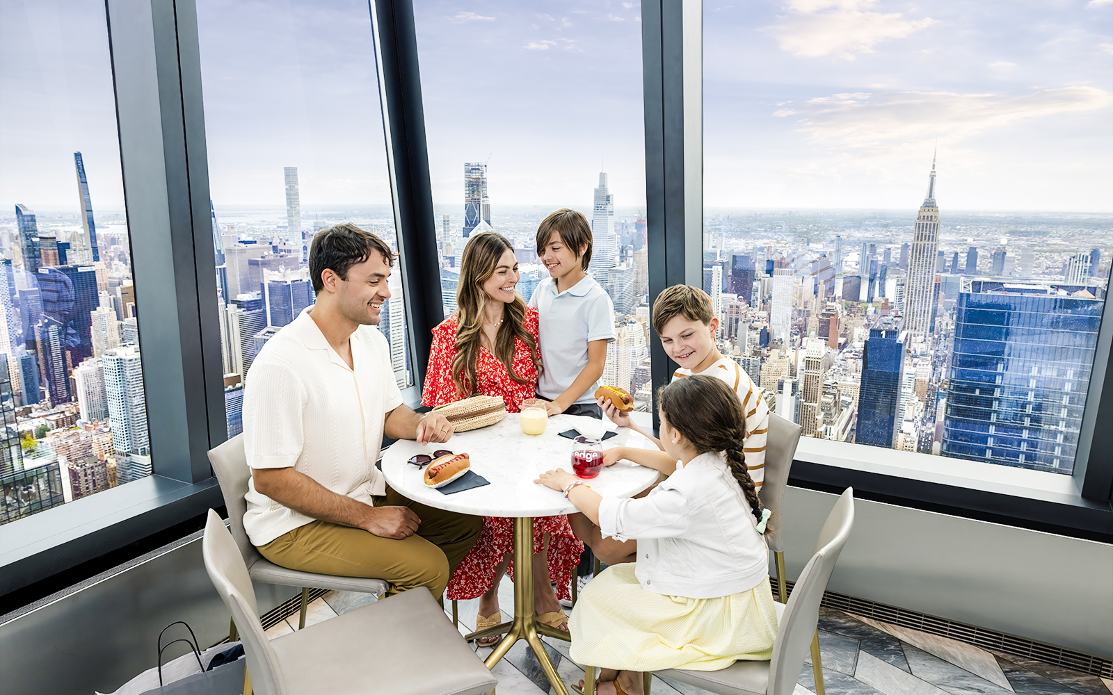 Family dining at Edge's indoor sky deck with New York City skyline views.