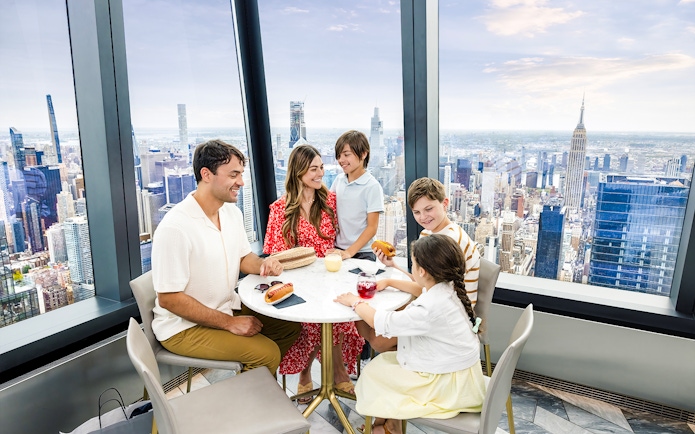 Family dining at Edge's indoor sky deck with New York City skyline views.