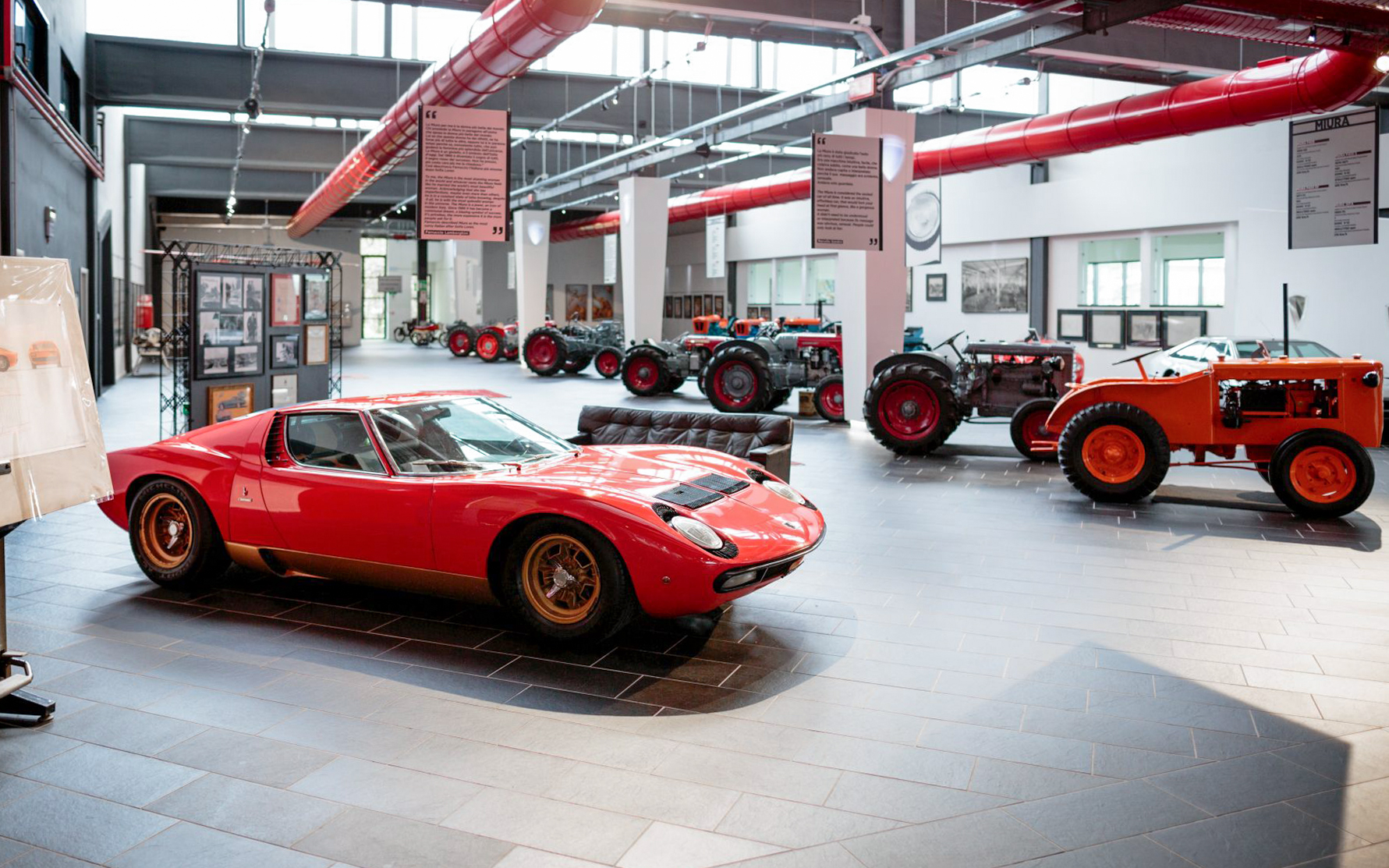 Red Lamborghini Miura and vintage tractors at Ferruccio Lamborghini Museum, Bologna, Italy.
