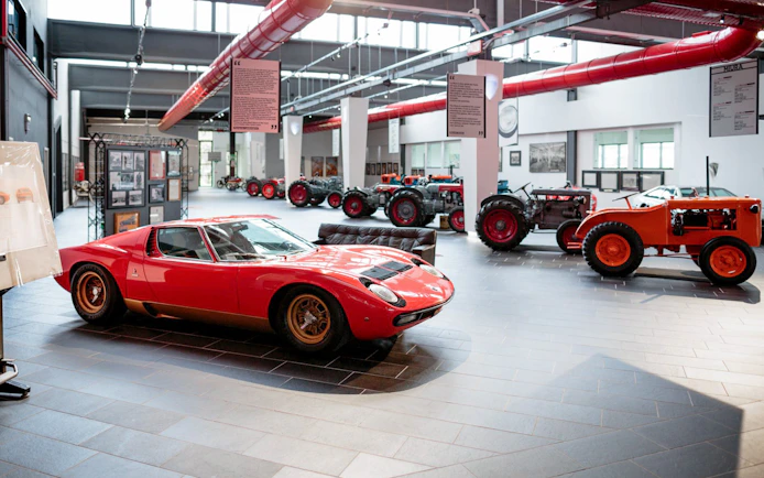 Red Lamborghini Miura and vintage tractors at Ferruccio Lamborghini Museum, Bologna, Italy.