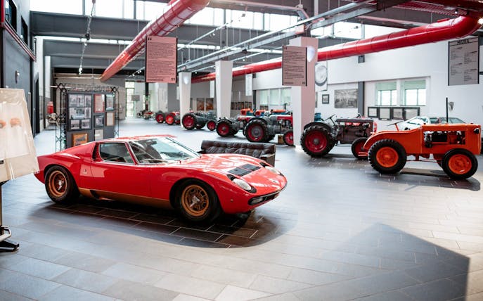 Red Lamborghini Miura and vintage tractors at Ferruccio Lamborghini Museum, Bologna, Italy.