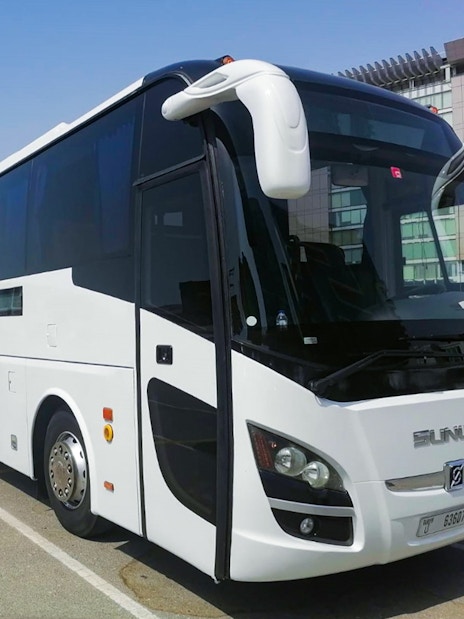 Tour bus for Dubai Safari Park transfers in a parking lot.