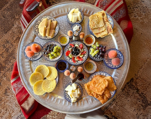 Traditional Berber breakfast spread with fruits and pastries in caidal tent, Marrakech.