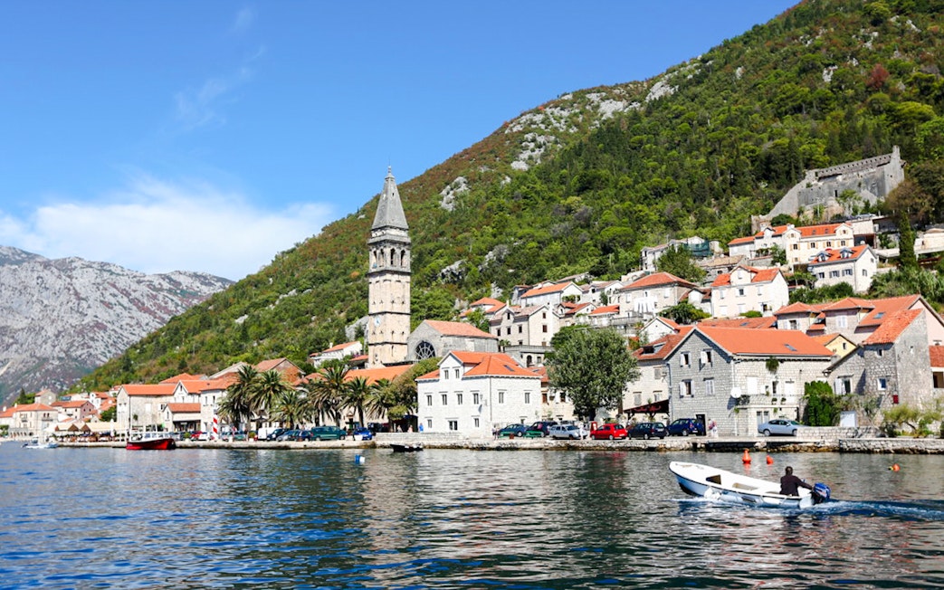 Perast town waterfront with bell tower and boat on the Bay of Kotor.