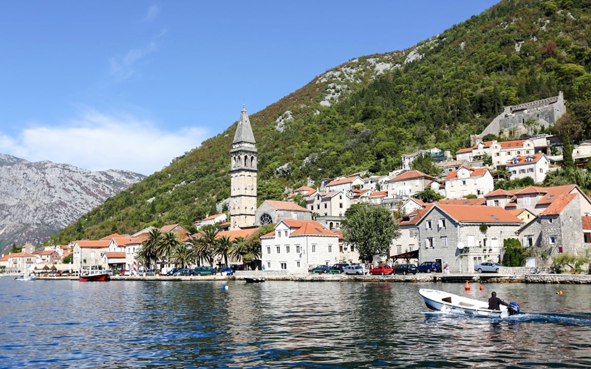 Perast town waterfront with bell tower and boat on the Bay of Kotor.