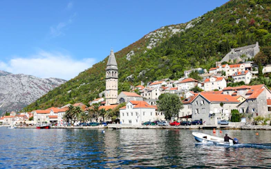 Perast town waterfront with bell tower and boat on the Bay of Kotor.