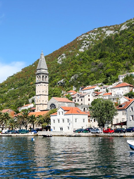 Perast town waterfront with bell tower and boat on the Bay of Kotor.